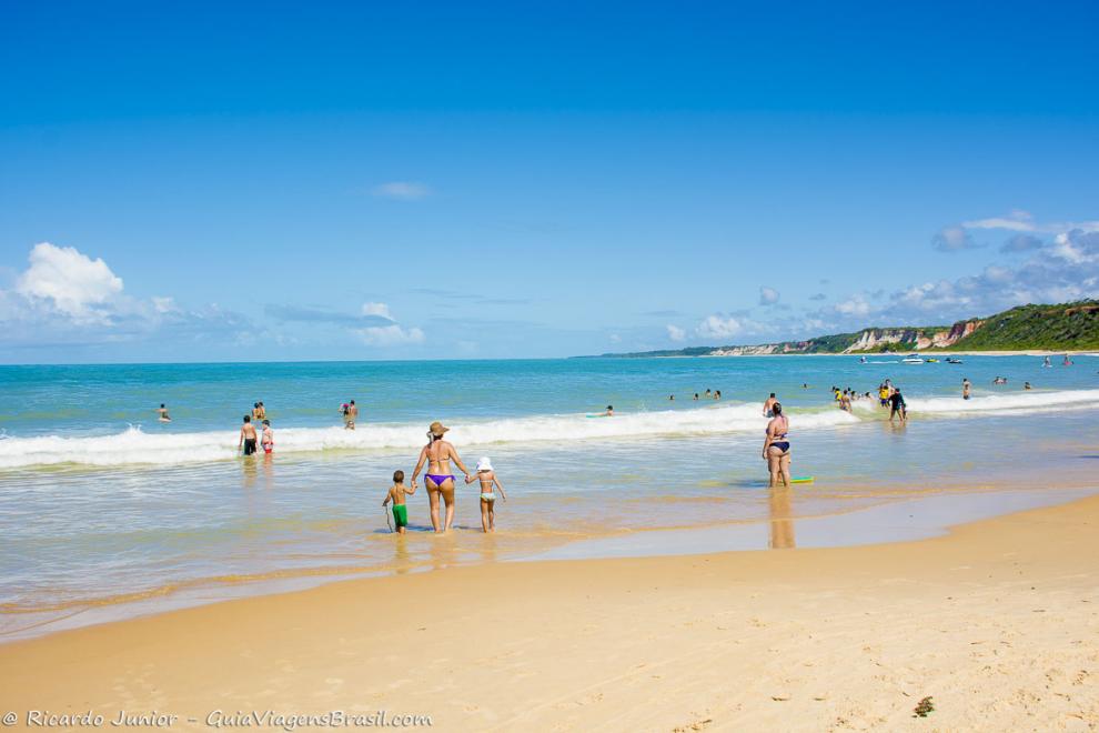 Imagem de famílias nas águas límpidas da Praia da Pitinga.